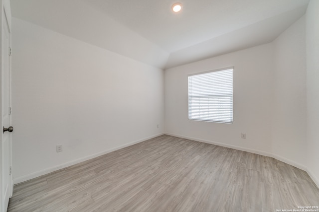 spare room featuring light hardwood / wood-style flooring and lofted ceiling