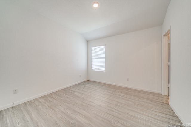 empty room with light hardwood / wood-style floors and vaulted ceiling