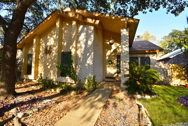 view of front of house featuring a chimney, a front lawn, and brick siding