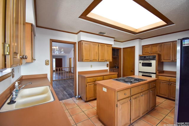 kitchen with sink, a center island, light tile patterned flooring, appliances with stainless steel finishes, and a textured ceiling