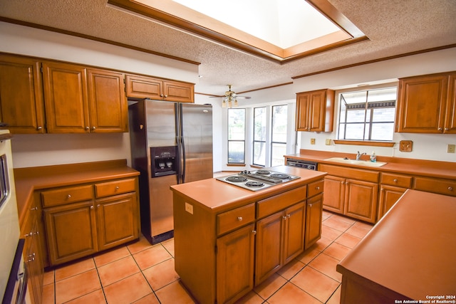 kitchen featuring sink, a textured ceiling, a center island, stainless steel appliances, and light tile patterned floors