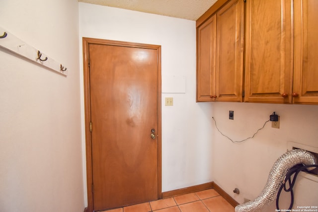 clothes washing area with light tile patterned floors, a textured ceiling, cabinets, and hookup for an electric dryer