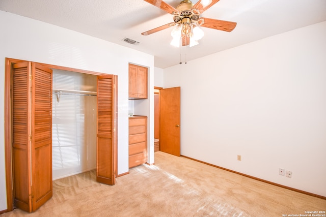 unfurnished bedroom with a closet, light colored carpet, and ceiling fan