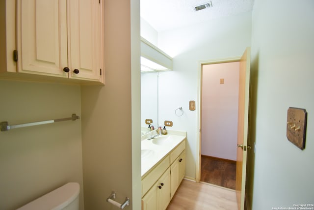 bathroom with vanity, a textured ceiling, hardwood / wood-style flooring, and toilet