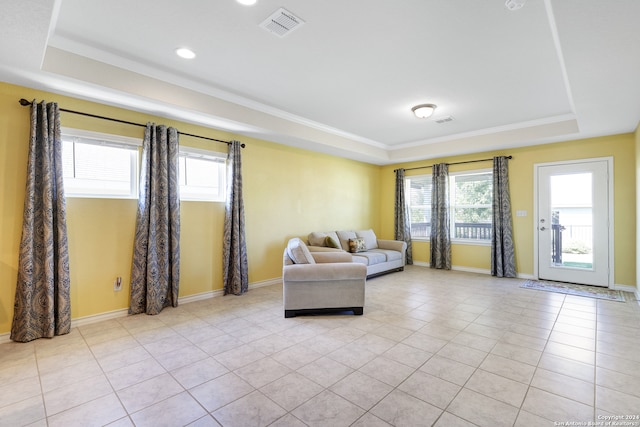 living room with light tile patterned floors, a healthy amount of sunlight, and a tray ceiling