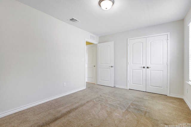 unfurnished bedroom featuring light carpet and a closet