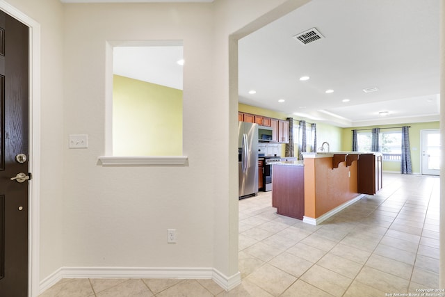 kitchen featuring a breakfast bar, appliances with stainless steel finishes, a kitchen island with sink, and light tile patterned flooring