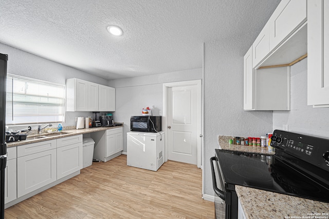 kitchen featuring black appliances, sink, light wood-type flooring, a textured ceiling, and white cabinetry