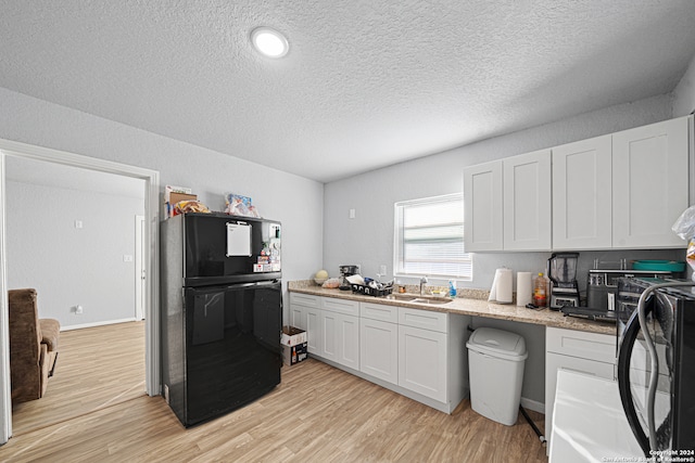 kitchen featuring light hardwood / wood-style floors, white cabinetry, black appliances, and a textured ceiling