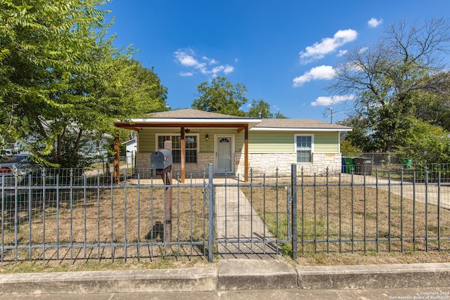 bungalow-style house featuring a porch, a gate, stone siding, and a fenced front yard