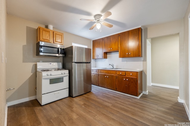 kitchen with sink, appliances with stainless steel finishes, wood-type flooring, and ceiling fan