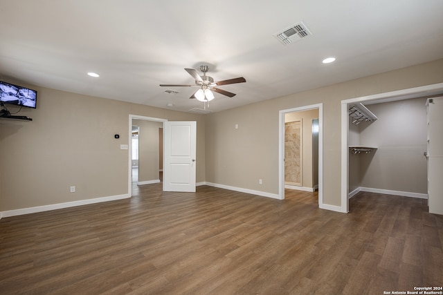 unfurnished bedroom featuring dark wood-type flooring, ceiling fan, a closet, and a spacious closet