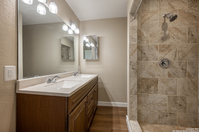 bathroom featuring vanity, a tile shower, and wood-type flooring