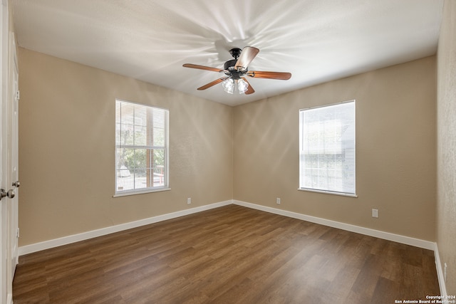 empty room with dark wood-type flooring, a healthy amount of sunlight, and ceiling fan