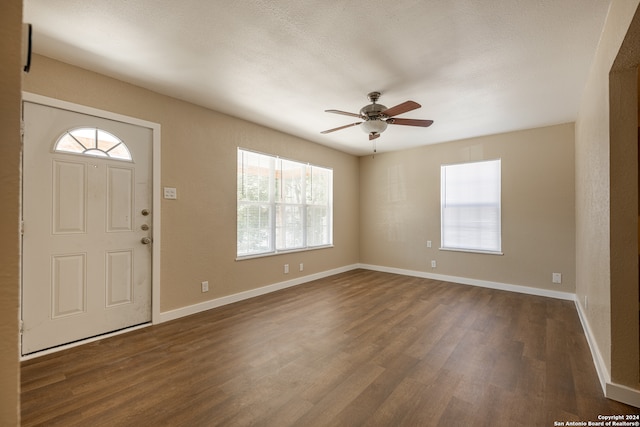 entrance foyer featuring a textured ceiling, a healthy amount of sunlight, dark wood-type flooring, and ceiling fan