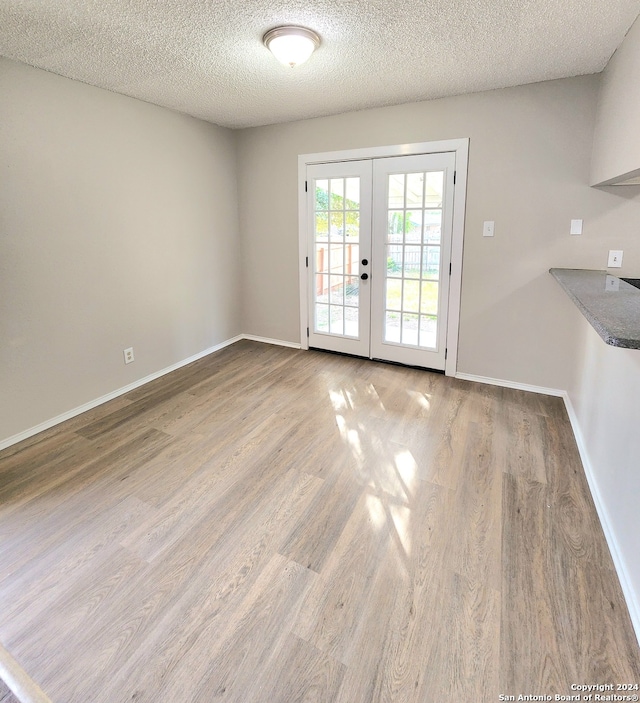 interior space with french doors, a textured ceiling, and light wood-type flooring