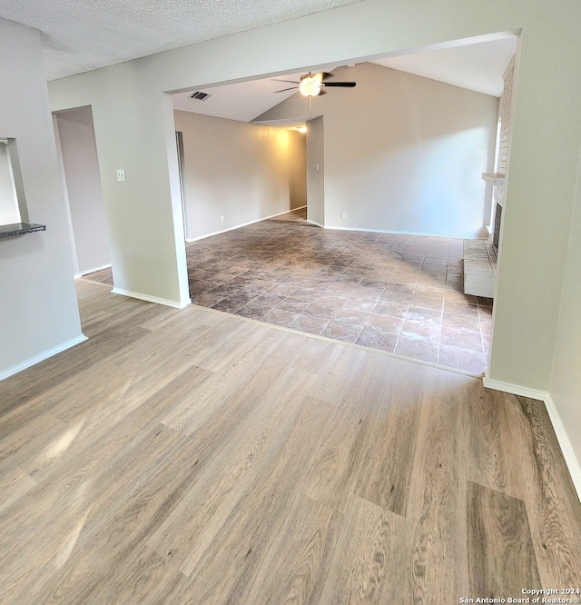 empty room featuring light hardwood / wood-style flooring, a textured ceiling, lofted ceiling, and ceiling fan