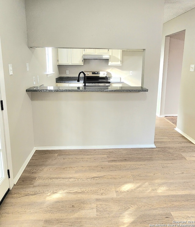 kitchen featuring white cabinetry, dark stone counters, stainless steel electric range oven, and light wood-type flooring