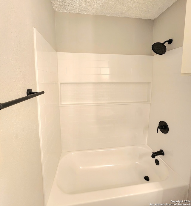 bathroom with a textured ceiling and shower / tub combination