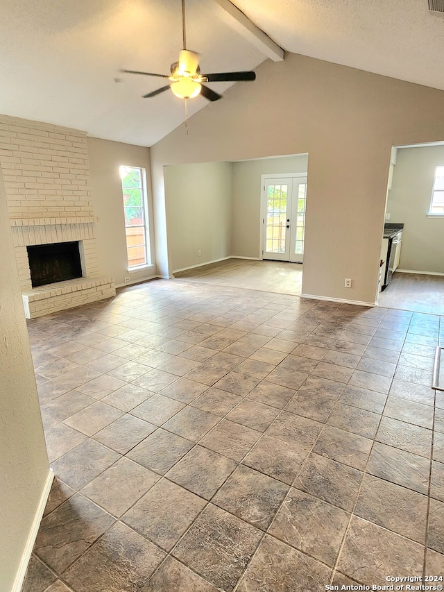 unfurnished living room featuring a brick fireplace, lofted ceiling with beams, ceiling fan, and a wealth of natural light