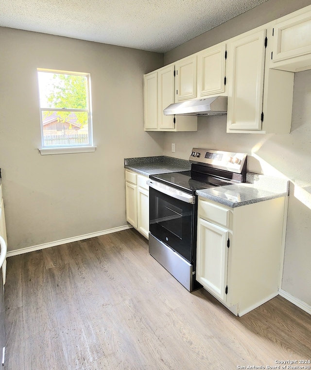 kitchen with a textured ceiling, white cabinets, stainless steel range with electric cooktop, and light wood-type flooring