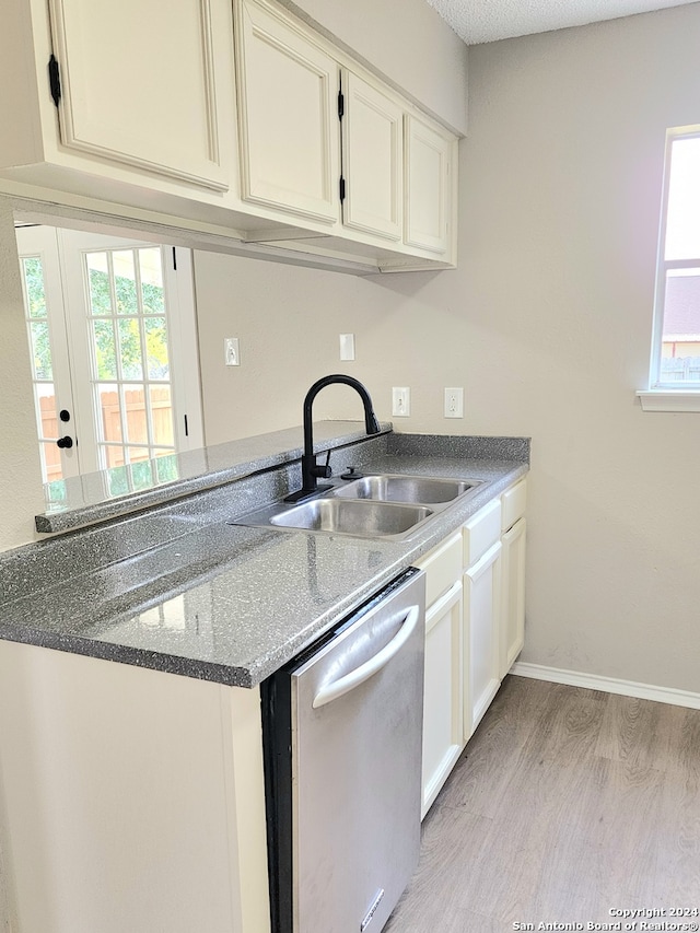 kitchen featuring sink, light wood-type flooring, a textured ceiling, white cabinetry, and stainless steel dishwasher