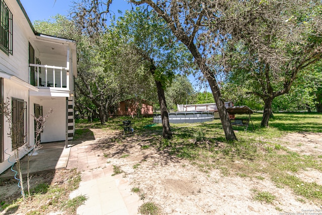 view of yard with a patio area, a pool, and a balcony