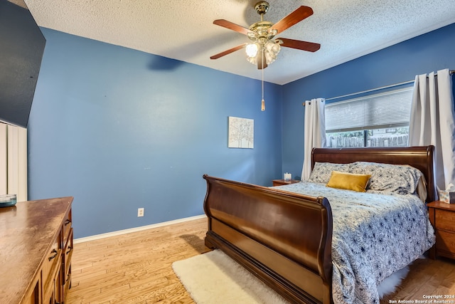 bedroom with a textured ceiling, light hardwood / wood-style floors, and ceiling fan