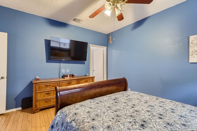 bedroom with ceiling fan, a textured ceiling, and light hardwood / wood-style floors