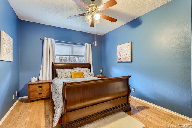 bedroom with light hardwood / wood-style floors, a textured ceiling, and ceiling fan