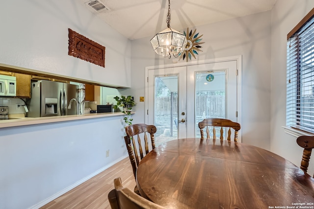 dining area featuring french doors, an inviting chandelier, and hardwood / wood-style floors