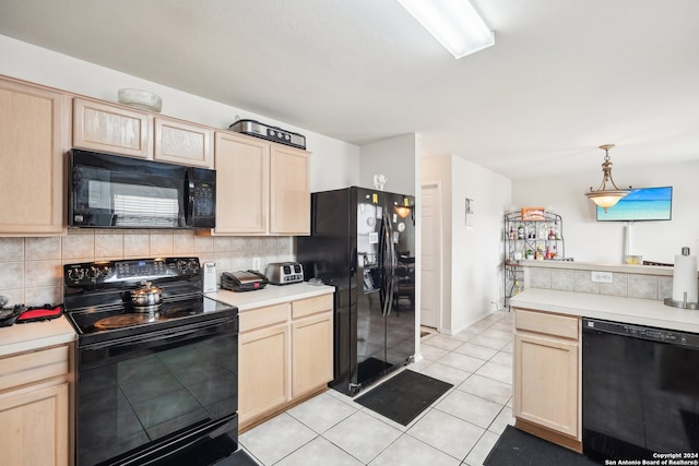 kitchen featuring backsplash, light brown cabinetry, light tile patterned flooring, black appliances, and decorative light fixtures