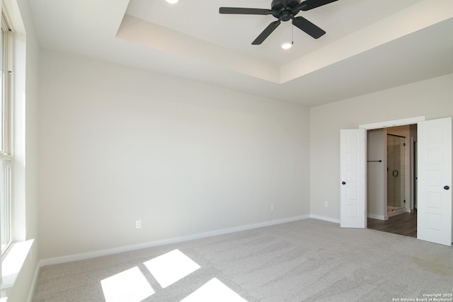 unfurnished bedroom featuring carpet, a tray ceiling, baseboards, and recessed lighting