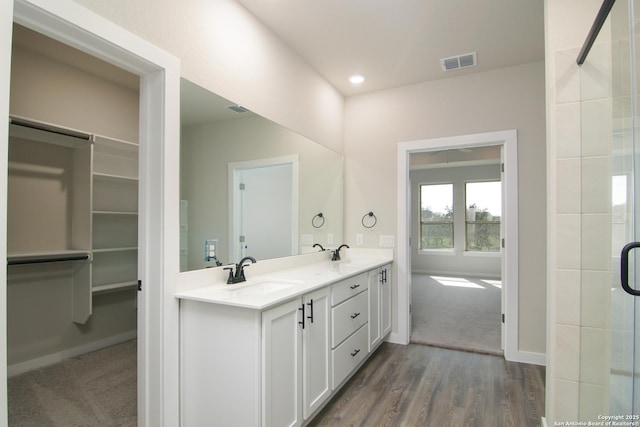 full bath featuring double vanity, a spacious closet, visible vents, and a sink