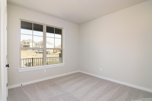 carpeted empty room featuring baseboards