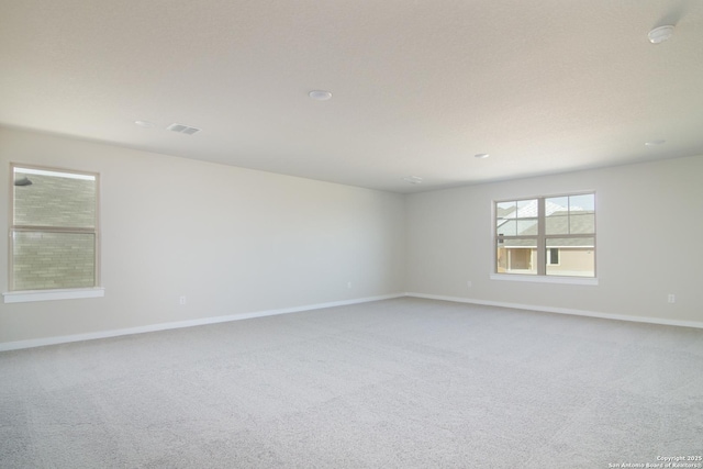 unfurnished room featuring carpet, visible vents, and baseboards