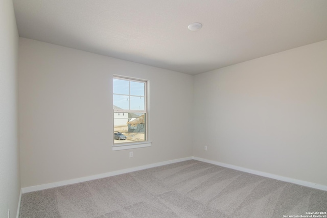 empty room featuring light colored carpet and baseboards