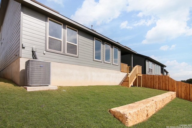 rear view of property with fence, a yard, stairway, and central air condition unit