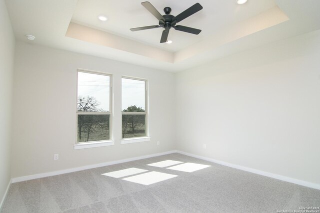 empty room featuring recessed lighting, carpet, a raised ceiling, and baseboards