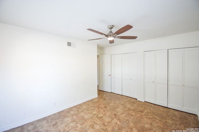 unfurnished bedroom featuring two closets and ceiling fan