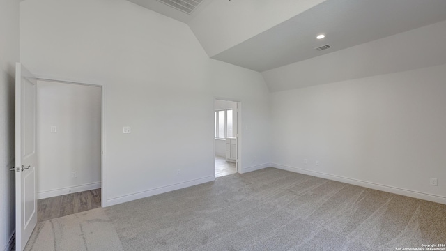 carpeted spare room featuring high vaulted ceiling