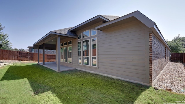 back of house with a patio area and a lawn