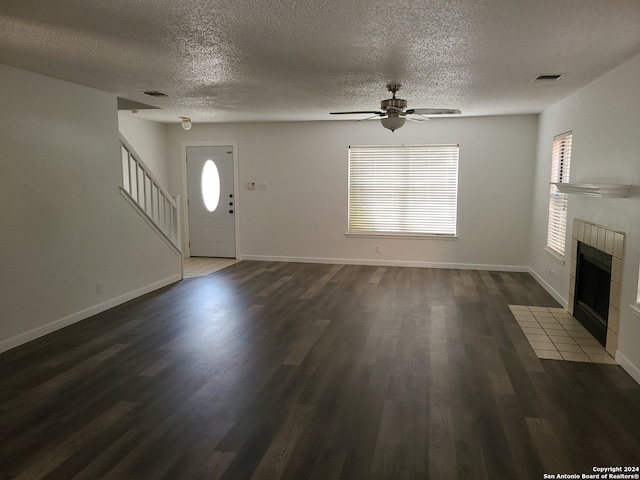 foyer entrance featuring ceiling fan, a textured ceiling, dark hardwood / wood-style flooring, and a fireplace