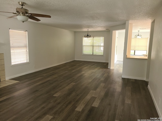 empty room featuring a healthy amount of sunlight, a textured ceiling, and dark hardwood / wood-style floors