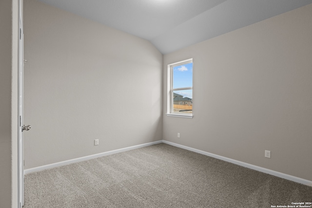 unfurnished room with carpet floors, baseboards, and vaulted ceiling