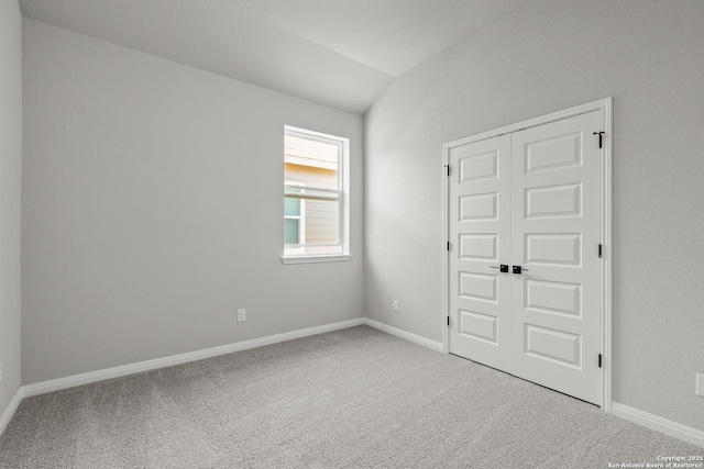 carpeted spare room with baseboards and lofted ceiling