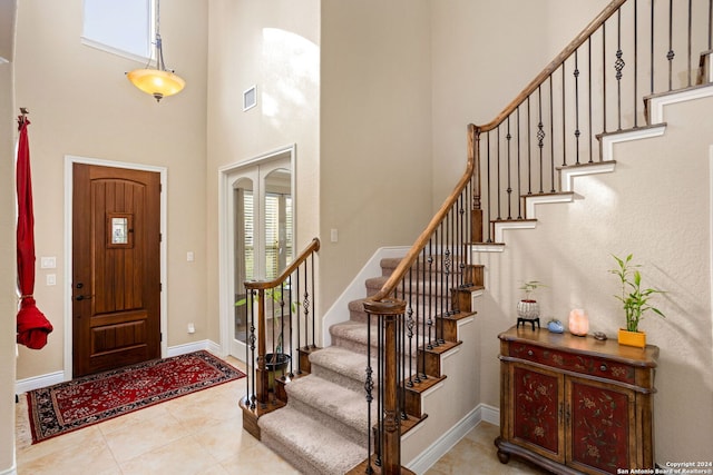 entryway with a towering ceiling and light tile patterned floors