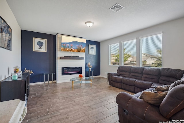 living room featuring a textured ceiling, hardwood / wood-style flooring, and a large fireplace