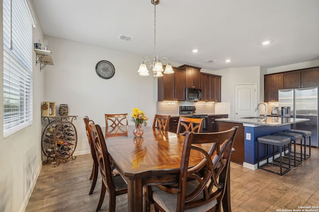 dining room with sink, a chandelier, and hardwood / wood-style flooring