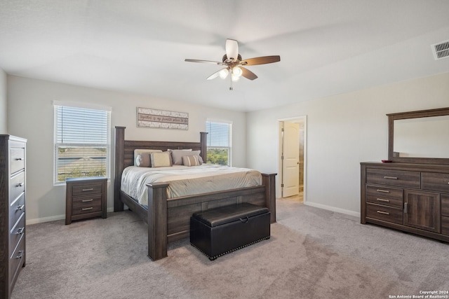 bedroom featuring ensuite bath, light colored carpet, and ceiling fan